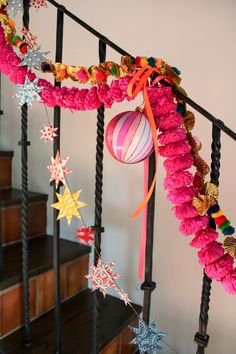 a staircase decorated with pink and gold garlands, stars, and ornaments on it