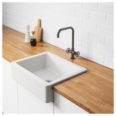 a white sink sitting on top of a wooden counter next to a faucet