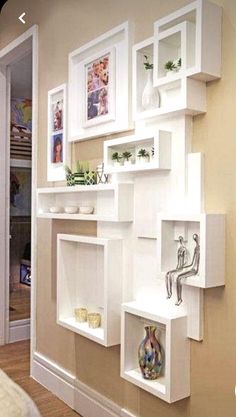 white shelves with pictures and vases on them in the corner of a living room