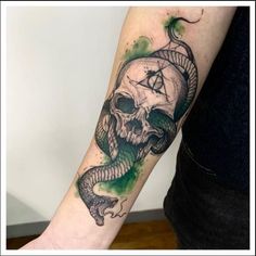 a person with a tattoo on their arm and a snake wrapped around the skull,