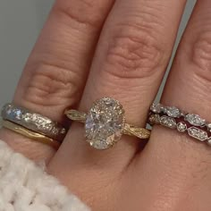 a woman's hand with three different rings on it and one has an oval shaped diamond