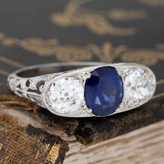 A beautiful Edwardian trilogy ring with all the antique charm one can wish for! Set with a deeply saturated blue Ceylon sapphire center and old mine cut shoulders, all in icy platinum with intricate filigree work throughout. The trio spans across the finger beautifully, with all that gallery detail coming in from all other angles! We’d love to see this ring worn as an engagement ring, or perhaps a bold pointer ring option. She sits low and comfortably on the finger too, making it a great daily p Pointer Ring, Modern Mens Rings, Art Jewelry Earrings, Saturated Blue, Trilogy Ring, Old Mine Cut Diamond, Ceylon Sapphire, Antique Watches, Antique Engagement