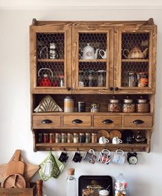 a wooden cabinet filled with pots and pans sitting on top of a kitchen counter