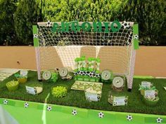 a soccer themed dessert table set up with cupcakes and snacks on the grass