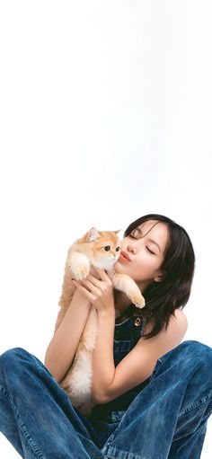 a woman is sitting on the floor holding a cat and kissing her face with both hands