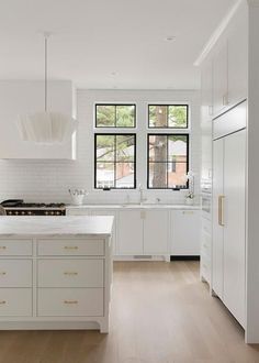 a large kitchen with white cabinets and wood flooring, along with an island in the middle