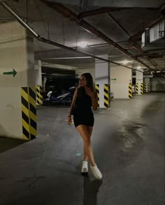 a woman is walking in an empty parking garage