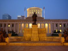 there is a statue in front of the state capitol building at night with lights on