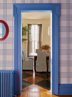 an open door leading to a dining room with blue walls and patterned chairs in it