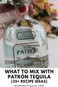 a hand holding a bottle of silver patron