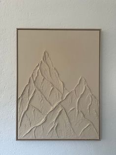 a painting hanging on the wall in front of a white wall with a brown frame