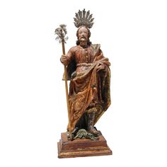 a statue of a man holding a staff and wearing an ornate crown, standing on a wooden base