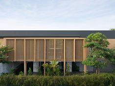 a building with wooden slats on the side and trees around it in front of some bushes