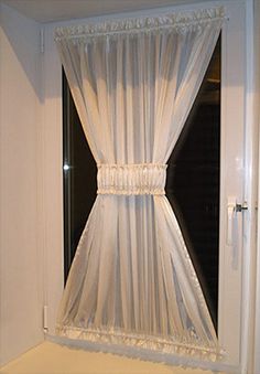 an open window with white curtains on it