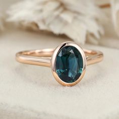 a close up of a ring with a blue stone in it on a white cloth