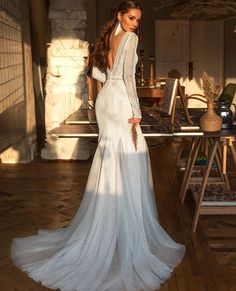 a woman in a white dress standing on a wooden floor with her back to the camera