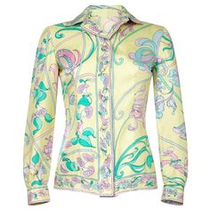 This late 1960s pastel toned silk blouse by Emilio Pucci is feminine, chic and in lovely vintage condition. The soft silk fabric has a abstracted floral design synonymous with its creator in soft shades of lemon, sugar pink, jade green and lilac. As with all of his pieces, the "Emilio" signature is incorporated subtly into the surface pattern. There is a central button stand hosting 6 silk covered buttons. The blouse can be fastened right up to the neck or be worn open as desired. The long sleev