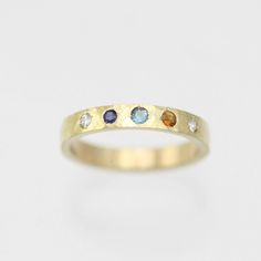 A colorful way to wear your family's birthstones! This ring is hand fabricated in solid 14ky gold and customized to use any number and combination of birthstones. The hammered texture gives the gold an extra glimmer! The ring is 3mm wide and 1.5mm thick. The stones are arranged in a straight line. Choose your ring size and desired number of birthstones when adding this item to your cart. Also, note the birthstone order from left to right in the text box. Please allow up to 14 business days for fabrication. Looks great stacked!!  Comes with a lifetime warranty, polishing cloth, and a gift box. All stones are synthetic except for Garnet, Amethyst, Peridot and Citrine which are natural. Feel free to ask for a price quote with all natural stones. Also available in sterling silver: https://www. 3 Birthstone Ring, 14k Yellow Gold Multi-stone Birthstone Ring, Multi-stone 14k Yellow Gold Birthstone Ring, Multi-stone Yellow Gold Birthstone Ring In 14k, Yellow Gold Multi-stone Birthstone Ring In 14k Gold, Anniversary Sapphire Ring With Recycled Gold, Yellow Gold Birthstone Ring In Recycled Gold, Mothers Ring Ideas, Family Birthstone Ring