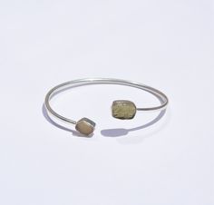 Begin your spiritual journey anew with our Libyan Desert Glass & Moldavite Bangle. Crafted in gleaming sterling silver, this bracelet blends the cosmic energy of Moldavite with the empowering properties of Libyan Desert Glass. Experience deep transformation and growth as these powerful gems harmonize within you, guiding you towards spiritual clarity and inner peace. Key Benefits & Features: Powerful Energy Duo: Harness the transformative properties of Moldavite and the empowering abilities of Libyan Desert Glass. Sterling Silver Craftsmanship: Enhances the natural energy of the gemstones. Adjustable Design: Ensures a comfortable fit and flexibility. Unique Piece: The open design makes a bold statement, symbolizing unity and personal transformation. Gemstone Properties: Moldavite: Stimulate Sterling Silver Bracelets With Natural Stones For Healing, Sterling Silver Bracelet With Natural Stones For Healing, Sterling Silver Fusion Bracelets, Adjustable Sterling Silver Fusion Bracelets, Spiritual Bracelet With Polished Finish, Silver Fusion Bracelets With Natural Stones, Spiritual Sterling Silver Gemstone Bangle, Sterling Silver Gemstone Fusion Bracelets, Spiritual Sterling Silver Bangle With Gemstone