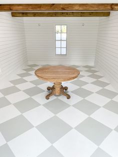 an empty room with a round table in the center and white tiles on the floor