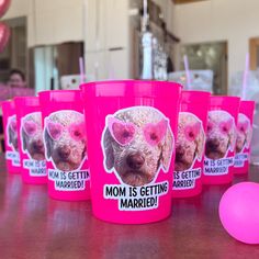 pink cups with pictures of dogs on them are sitting on a table next to a ball