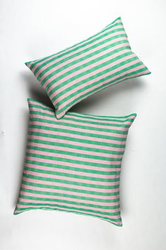 two green and white striped pillows sitting next to each other