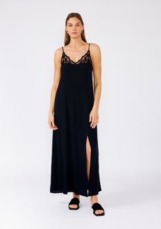 [Color: Black] A front facing image of a brunette model wearing a classic black maxi slip dress with lace detail along the neckline. With adjustable spaghetti straps Summer Evening Slip Dress With Delicate Lace, Sleeveless Evening Slip Dress With Delicate Lace, Black Maxi Slip Dress With Adjustable Straps, Night Midi Dress With Spaghetti Straps, Chic V-neck Maxi Dress For Night, Elegant V-neck Maxi Dress With Lace Trim, Elegant Maxi Slip Dress With Lace Trim, Elegant Cami Dress With Lace Trim, Elegant Lace Trim Slip Dress For Date Night