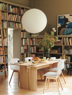 a dining room table surrounded by bookshelves and chairs