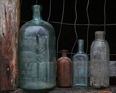 old glass bottles are lined up against a wire fence