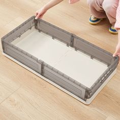 a child is playing with a plastic toy box on the floor in front of her