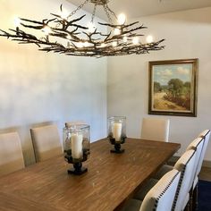 a chandelier hanging over a dining room table with candles in front of it