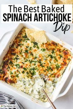 A casserole dish of baked spinach artichoke dip with golden brown melted cheese and a few tortilla chips on top. A serving spoon has broken the surface to reveal its creamy interior. There is text overlay saying, The Best Baked Spinach Artichoke Dip.