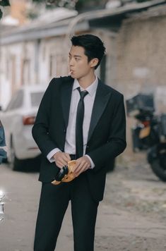 a man in a suit and tie standing next to a parked car on the street