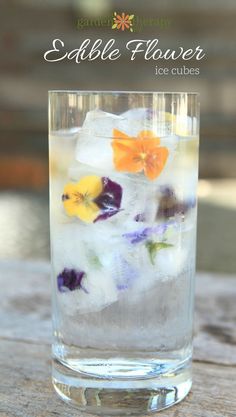 a glass filled with ice and flowers on top of a wooden table