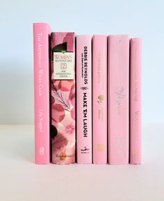 four pink books are stacked on top of each other