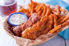 fried fish and french fries in a basket with dipping sauce on the side, ready to be eaten