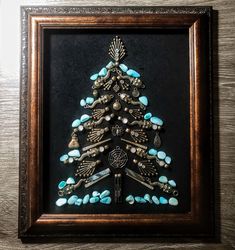 a framed christmas tree with turquoise stones and other items in it's shadow box