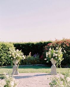 two vases filled with flowers sitting in the middle of a garden