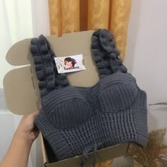 someone holding up a box with a knitted hat in it's front and back