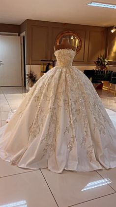 a wedding dress is on display in the middle of a room with white tile flooring