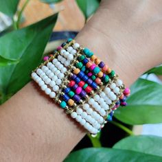 a woman's arm with a bracelet made out of beads and other colorful beads