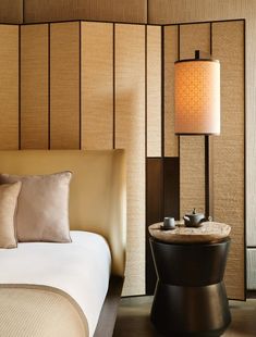 a hotel room with a bed, table and lamp