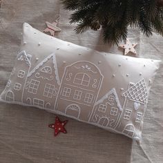 a white pillow sitting on top of a table next to a christmas tree and decorations