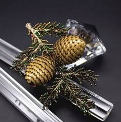 two pinecones are sitting on top of some silver utensils with green beads