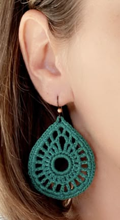 a woman wearing green crochet earrings with gold earwires on her ears