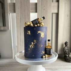 a blue cake with gold sprinkles and two bottles of liquor on top