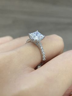 a woman's hand with a diamond ring on top of her finger and an engagement band