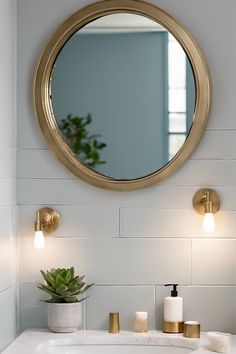 Modern bathroom with round brass mirror, wall sconces, and a marble countertop with a potted succulent and soap dispensers. Double Vanity Mirrors, Bathroom Mirror And Lighting Ideas, Bathroom Mirror And Lighting, Oversized Round Mirror, Mirror Design Ideas, Full Wall Mirror, Bathroom Mirror Design, Mirror Gallery, Bathroom Mirror Ideas