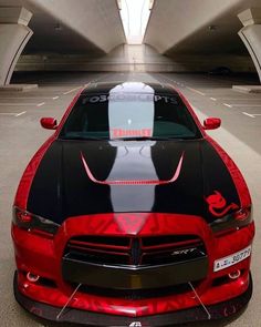 a red and black sports car parked in a parking garage next to an overpass