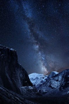 the night sky is filled with stars above mountains and snow capped peaks in the foreground